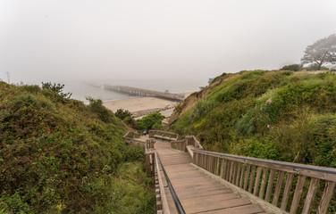 Fototapeta na wymiar Aerial View of Long Wooden Stairs to the Beach With Fog over Pier