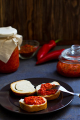 Fototapeta na wymiar ajvar, appetizer of baked peppers on the table, bread with ajvar, toast with ajvar, balkan appetizer of baked peppers, vertical, space for your text