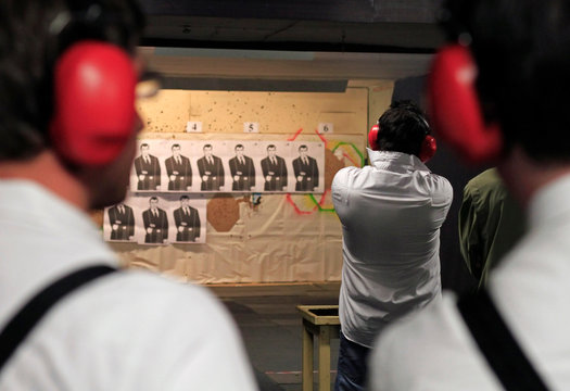 Young man with a gun at a shooting range seen from behind