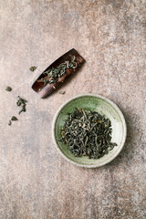 Dried Green Tea Leaves on Rustic Background. Top view. Copy space. 