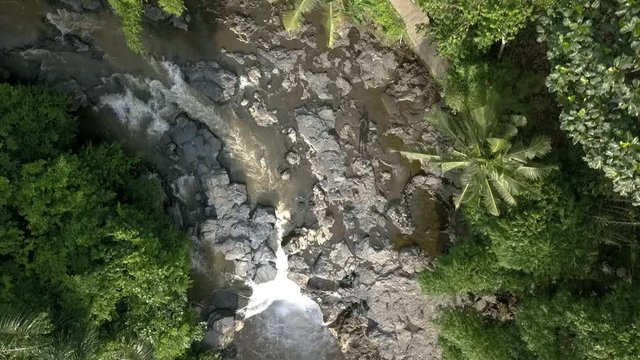 AERIAL FLYING OVERHEAD A WATERFALL, Tegenungan, beautiful river course in Bali, Indonesian. Surrounding by trees.