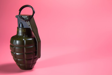 Green metal hand Grenade with round pin over When I pull out it will blow Bomb On a pink background