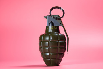 Green metal hand Grenade with round pin over When I pull out it will blow Bomb On a pink background