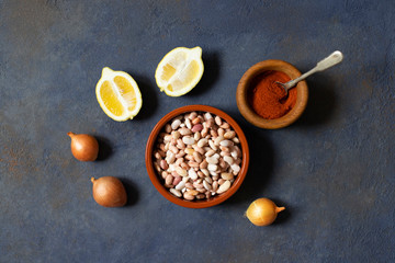 Prebranac ingredients. Balkan baked beans. Serbian, Montenegrin, Bosnian, Croatian and Slovenian cuisine. Uncooked beans, onion, lemon, paprika powder. Dark background. Top view. Space for text