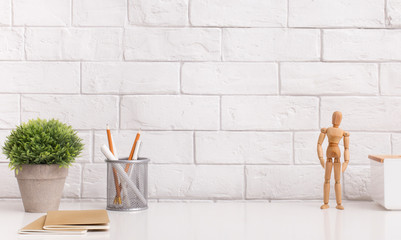 Table with stationery and wooden mannequin in modern office