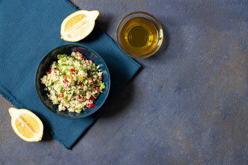 Tabbouleh salad with couscous, parsley, lemon, tomato, olive oil. Levantine vegetarian salad. Lebanese, arabic cuisine. Dark background. Top view. Space for text