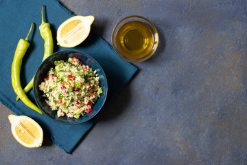 Tabbouleh salad with couscous, parsley, lemon, tomato, olive oil. Levantine vegetarian salad. Lebanese, arabic cuisine. Dark background. Top view. Space for text