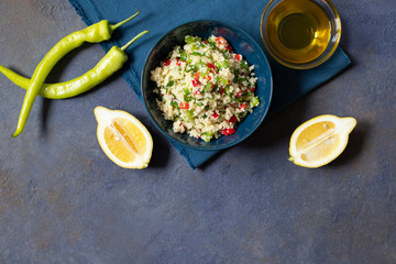 Tabbouleh salad with couscous, parsley, lemon, tomato, olive oil. Levantine vegetarian salad. Lebanese, arabic cuisine. Dark background. Top view. Space for text