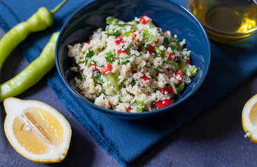 Tabbouleh salad with couscous, parsley, lemon, tomato, olive oil. Levantine vegetarian salad. Lebanese, arabic cuisine. Dark background. Close up view