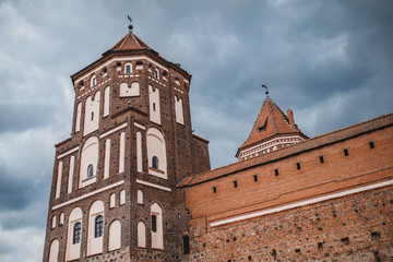 Fototapeta na wymiar Square tower and massive impregnable walls of an old medieval red brick castle