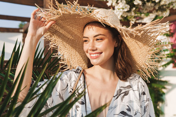 Positive happy young beautiful woman at the beach walking in a beautiful sunny morning over tropical plants.