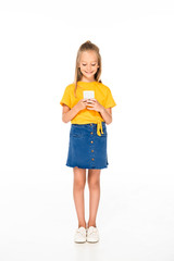 full length view of cute, smiling child using smartphone on white background