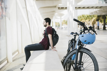 Fototapeta na wymiar Sideways man sitting next to electric bicycle