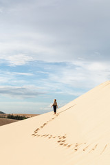 Fototapeta na wymiar Female silhouette walking in desert sand dunes of Mui Ne, Vietnam