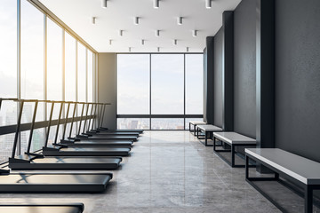 Modern light loft style gym interior with black treadmiils.