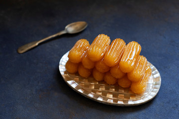 Traditional dessert called tulumba. Turkish cuisine. Balkan cuisine. Levantine cuisine. On a blue background, served on a vintage oriental plate