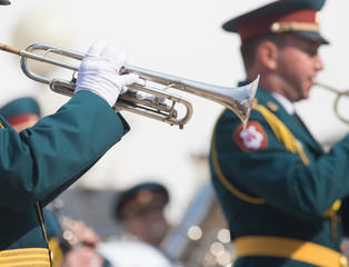 A wind instrument parade - a man in green costume playing trumpet