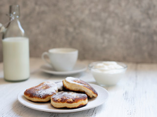 Cottage cheese pancakes, Cheesecakes on the table. Syrniki or sirniki. Healthy breakfast. White dishes. Bottle of milk. A cup of milk. Yogurt or sour cream. White background. Close up