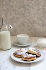 Cottage cheese pancakes, Cheesecakes on the table. Syrniki or sirniki. Healthy breakfast. White dishes. Bottle of milk. A cup of milk. Yogurt or sour cream. White background. Close up