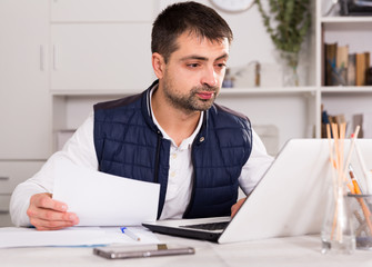 Businessman in shirt working with laptopt and documents