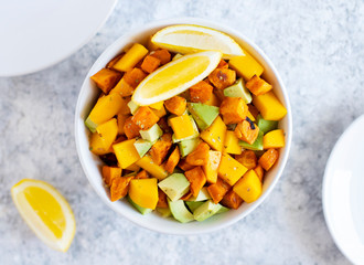 Pegan salad with mango, avocado and sweet potatoes, served with lemon water. Paleo diet. Pegan diet. Vegetarian food. Light background