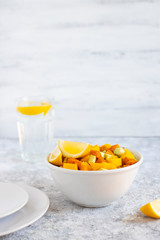 Pegan salad with mango, avocado and sweet potatoes, served with lemon water. Paleo diet. Pegan diet. Vegetarian food. Light background