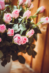 Gorgeous bouquet of flowers in a white pot. Pink and raspberry roses in a vase on the window.
