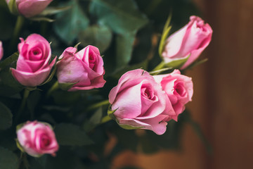 Gorgeous bouquet of flowers in a white pot. Pink and raspberry roses in a vase on the window.