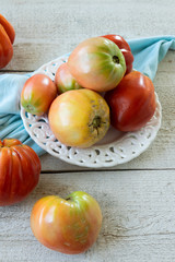 Raw ripe graden tomatoes on wooden background. Vegetarian ingredients, seasonal produce.