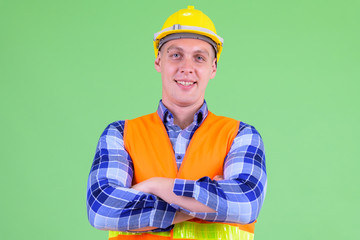 Happy young man construction worker smiling with arms crossed