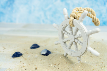 Maritime background with sand, shells and an old white wooden wheel