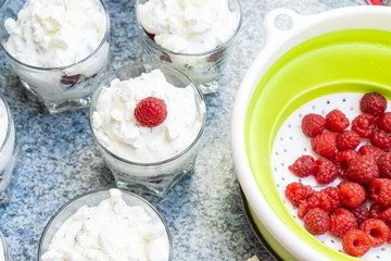 Making fresh cream dessert in glasses with fresh raspberries