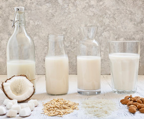 Assortment of healthy organic vegan milk. Almond, rice, oat and coconut milk. Light wooden background. Front view.