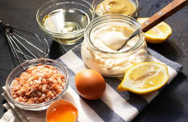 Mayonnaise sauce and ingredients for fresh homemade mayonnaise. Dark background. Close-up view