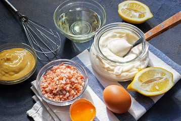 Mayonnaise sauce and ingredients for fresh homemade mayonnaise. Dark background. Close-up view