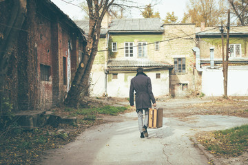 Rear view of a man walking with suitcase.