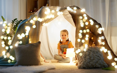 childhood and hygge concept - happy little girl with toys in kids tent at home © Syda Productions