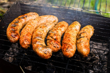 Grilled bavarian sausages on grate during cooking.