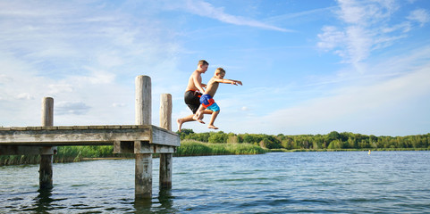 lachende Kinder springen vom Steg