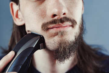 guy shaves his beard with an electric razor