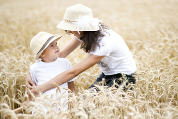 Naklejka na ściany i meble Happy brother and sister having fun on the field with wheat. Summer vacation time