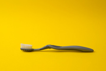 Two different grey  toothbrushes on a yellow background. All you need for teeth.