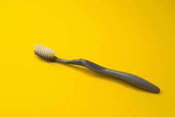 Two different grey  toothbrushes on a yellow background. All you need for teeth.