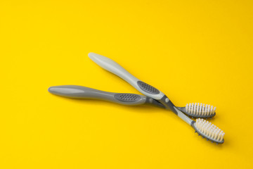 Two different grey  toothbrushes on a yellow background. All you need for teeth.