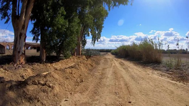 4K. Ultra HD. Cycling on a dirt road, wheel, with trees and plants around, natural panoramic of the environment with a blue sky with numerous clouds. Nature.