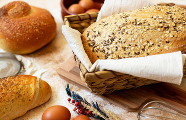 Bakery Concept. An assortment of different types of bread on a light marble background. Eggs, flour, wheat ears. Close-up