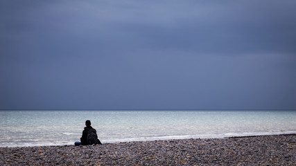 man sitting in contemplation at beach