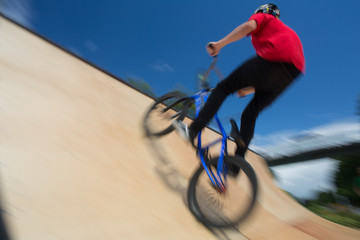  Bmx rider jumping over on a U ramp in a skatepark (motion blurred image)