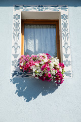Old blue window with flowerbox full with pink flowers.