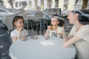 Mother with children drinking hot chocolate and latte at a local coffee shop. They are smiling and having fun.